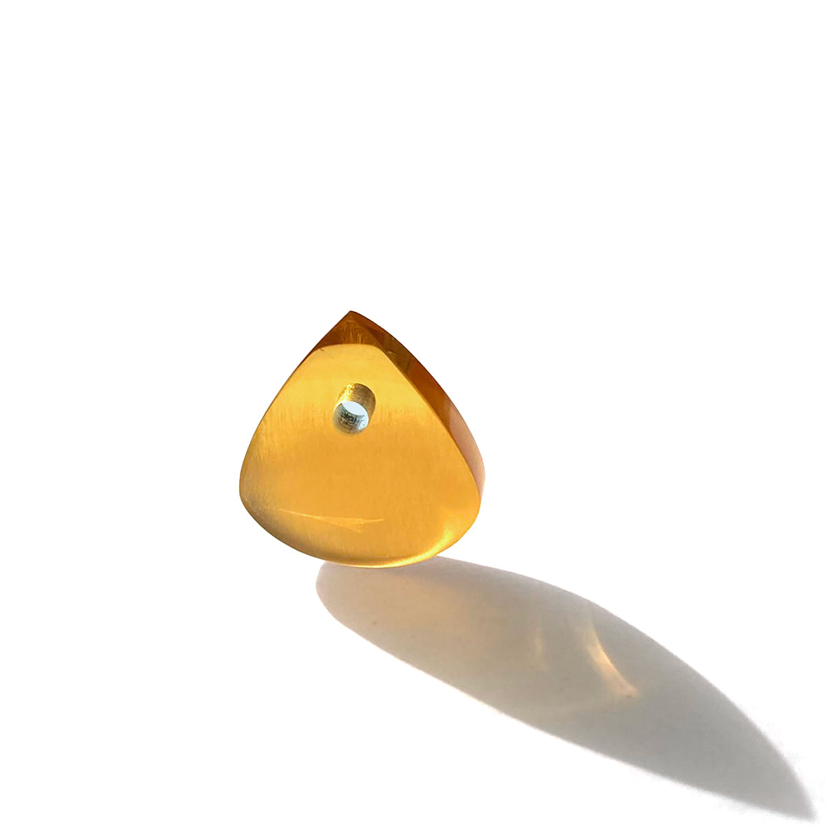 Amber colored plectrum bathed in sunlight against white background 