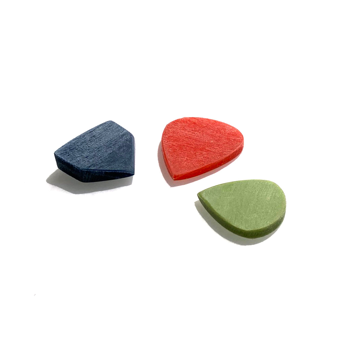 Three guitar picks blue, orange and green against white background under sunlight